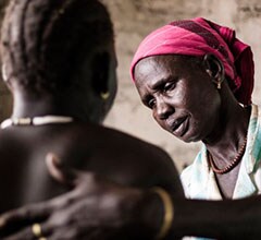 Pregnant woman being helped by midwife Red Cross